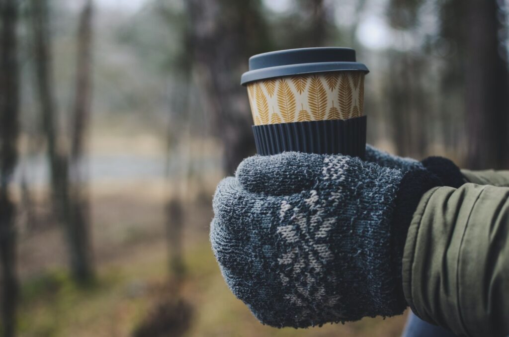 A pair of warm winter gloves holding a cup of coffee, with a shallow depth of field
