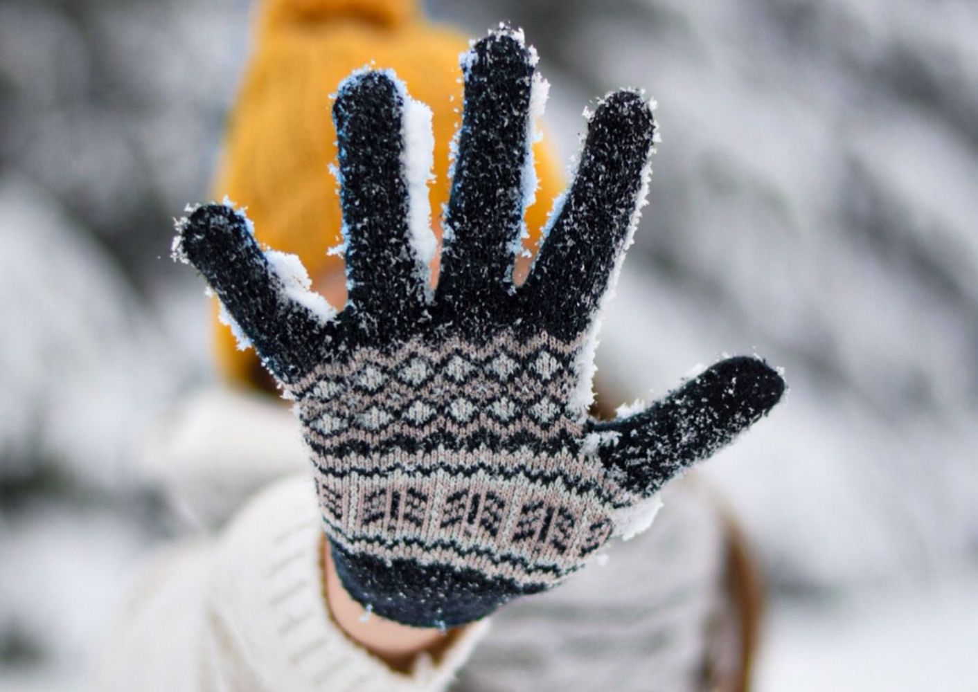 A child holding out their gloved, snow-covered hand to the camera.